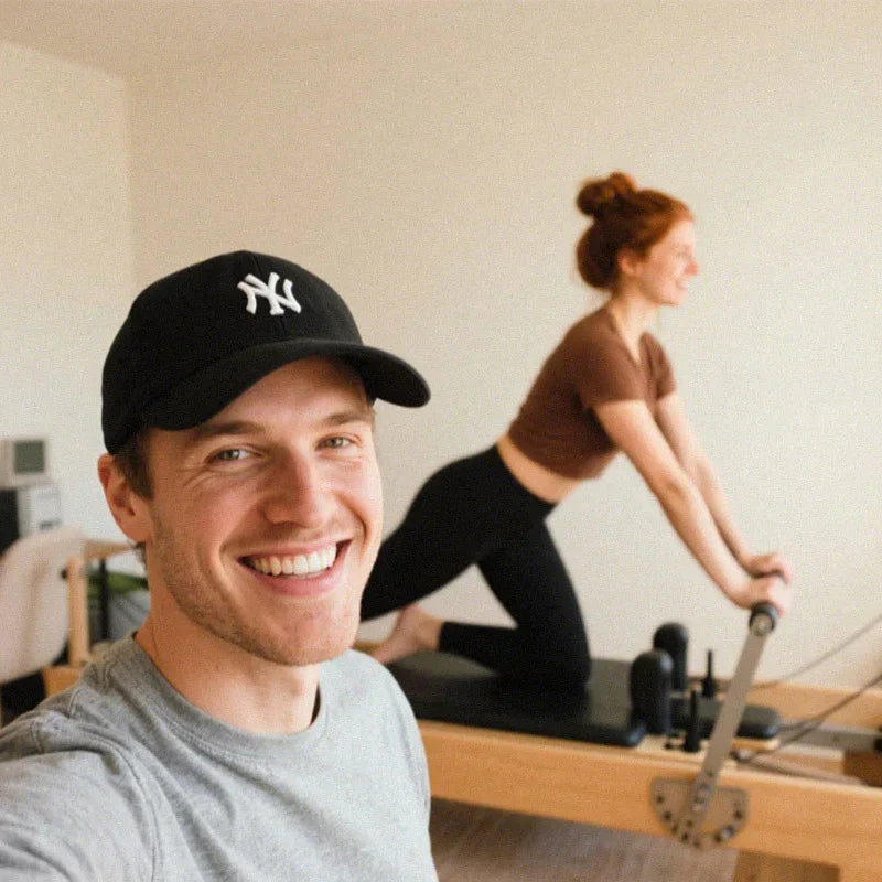 Customer selfie with a Joyrider Pilates reformer in use in the background, testimonial photo